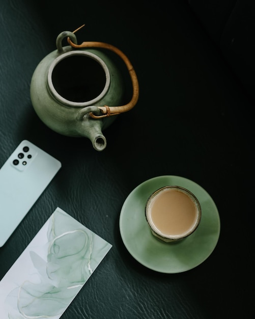 Vue de dessus de la théière et du verre de thé au lait et du smartphone. Petit-déjeuner anglais traditionnel thé noir wit