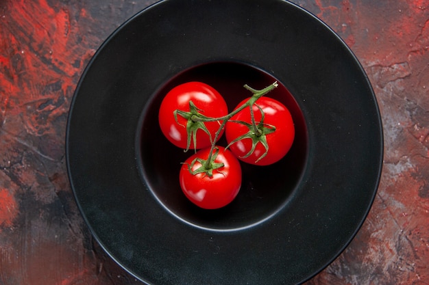 vue de dessus tomates rouges fraîches à l'intérieur de la plaque noire sur une surface sombre régime alimentaire repas légumes salade horizontale aliments santé