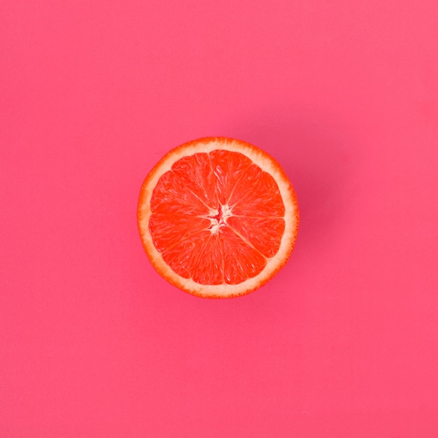 Vue de dessus d&#39;une tranche de pamplemousse sur fond clair de couleur rose pâle. Une image de texture d&#39;agrumes saturée