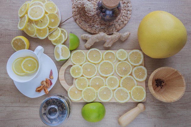 Photo vue de dessus des tranches de citron agrumes gingembre sur une composition de table en bois avec des ustensiles de cuisine