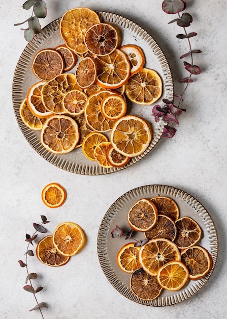 Vue de dessus des tranches d'orange séchées sur des assiettes en céramique avec des branches d'eucalyptus