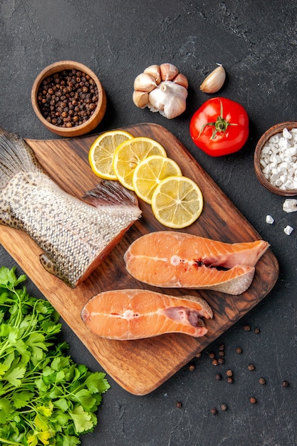 vue de dessus tranches de poisson frais avec citron et légumes verts sur fond gris foncé salade de poisson eau océan mer dîner fruits de mer