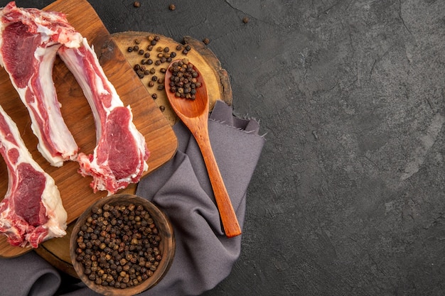 Vue de dessus des tranches de viande crue avec du poivre sur un fond gris foncé photo de viande de couleur de vache poulet au poivre animal cru