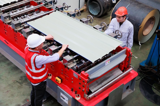 Vue de dessus Travailleur ingénieur d'usine utilisant une machine de toit en tôle dans l'industrie lourde Ouvrier d'usine portant un casque de sécurité dans les installations industrielles de l'usine