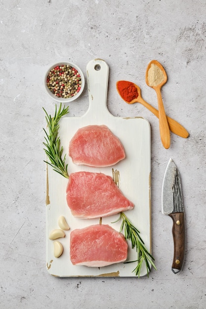 Vue de dessus de trois escalopes de porc non cuites entourées d'épices