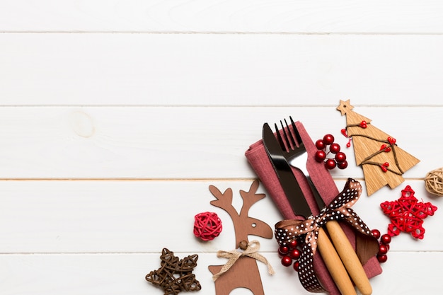 Photo vue de dessus des ustensiles de nouvel an sur la serviette avec des décorations de fêtes et des rennes sur fond en bois. dîner de noël avec fond