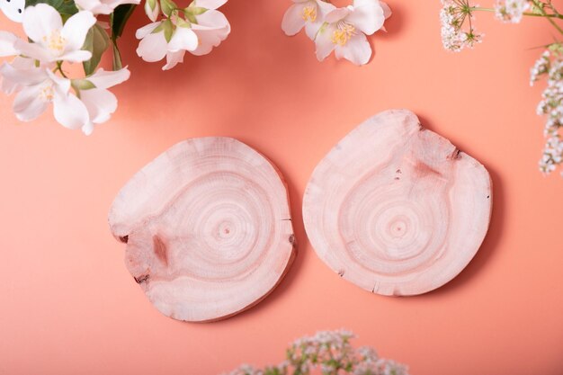 Vue de dessus vatural beauté minimale socle en bois Podiums de cosmétiques vides sur fond orange avec des fleurs pour produit ou bijoux