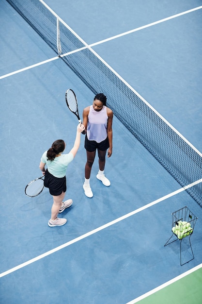 Vue de dessus verticale de l'entraîneur de tennis féminin travaillant avec le client contre l'espace de copie du sol de la cour bleue