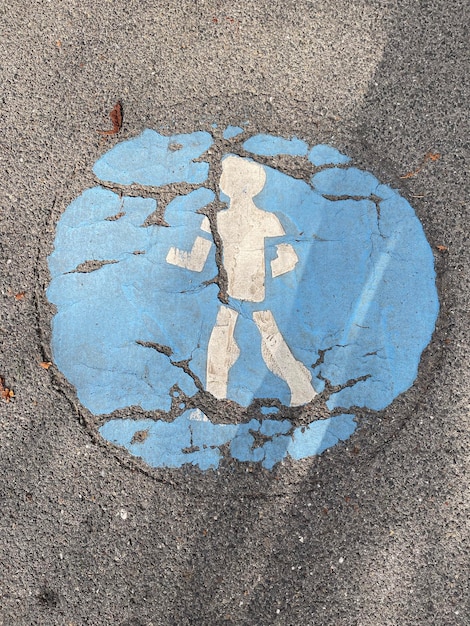 Vue de dessus verticale d'un panneau piéton fissuré peint sur le trottoir