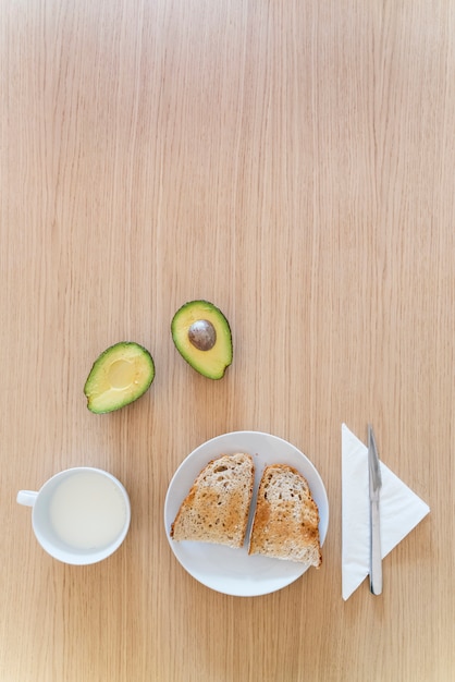 Vue de dessus verticale de table au petit déjeuner avec des aliments sains. Pain toast avocat traditionnel et lait frais.