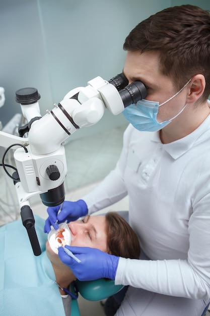 Vue de dessus verticale tourné d'un dentiste masculin à la recherche en microscope dentaire tout en travaillant