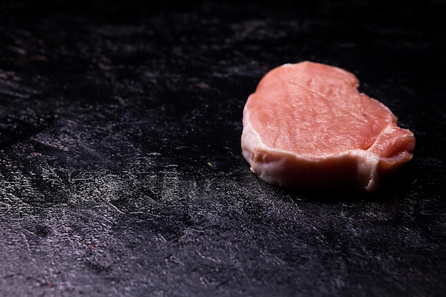 Vue de dessus de la viande crue fraîche sur une table en bois noire. Cuisine gastronomique et repas frais non cuits