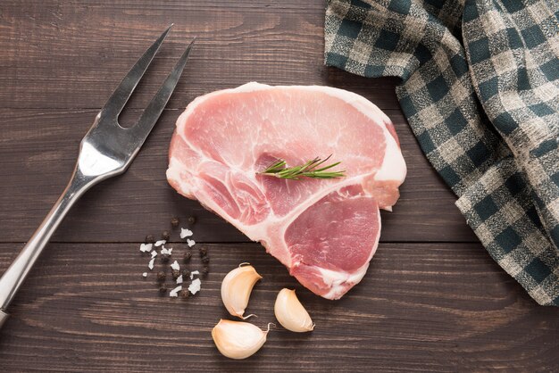 Vue de dessus de viande fraîche crue et sel, poivre, ail sur table en bois