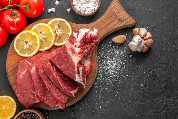 vue de dessus de la viande fraîche en tranches avec des tranches de citron et des tomates rouges