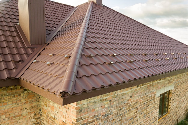 Vue détaillée du toit de la maison recouvert de feuilles de tuiles métalliques marron