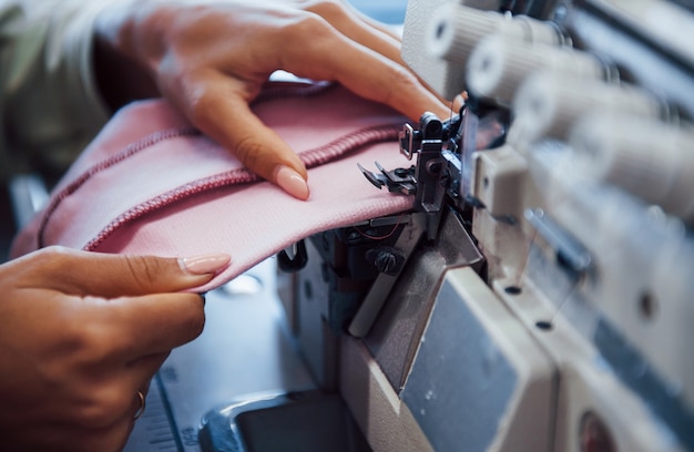 Vue détaillée de la femme couturière coud des vêtements sur une machine à coudre en usine.