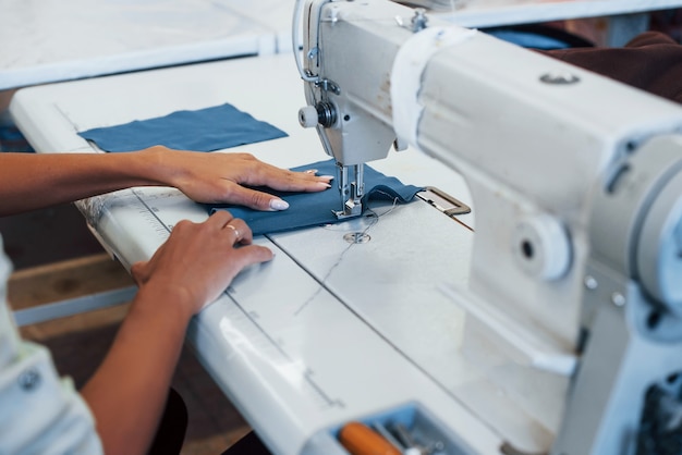 Vue détaillée de la femme couturière coud des vêtements sur une machine à coudre en usine.