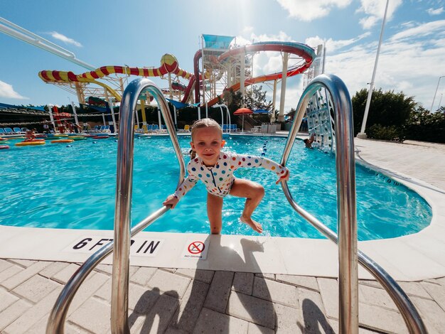 Photo vue de devant d'un enfant sortant de la piscine avec un ciel bleu vif