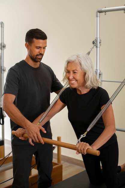 Photo vue de devant un homme aidant une femme en cours de pilates