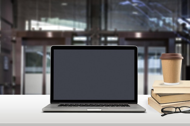 Vue de devant de l'ordinateur portable sur le bureau sur le fond flou du bureau