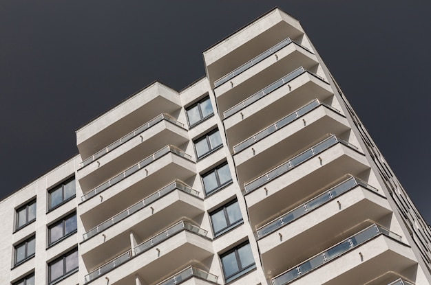 Vue diagonale au sol de l'immeuble de luxe moderne avec balcon et fenêtres, surface du ciel sombre le jour de pluie orageux