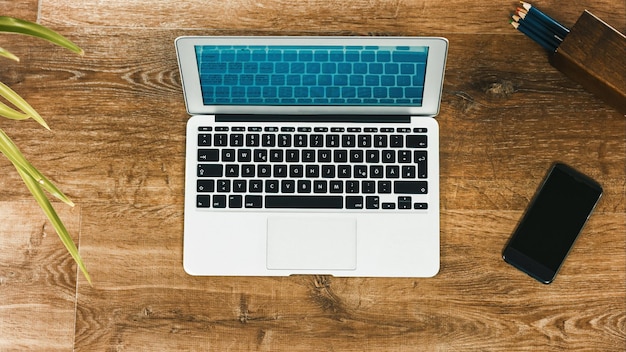 Vue directement au-dessus de l'ordinateur portable avec le téléphone portable sur la table