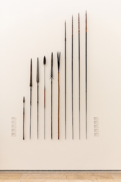 Photo vue de diverses lances anciennes dans un musée sur un mur blanc.