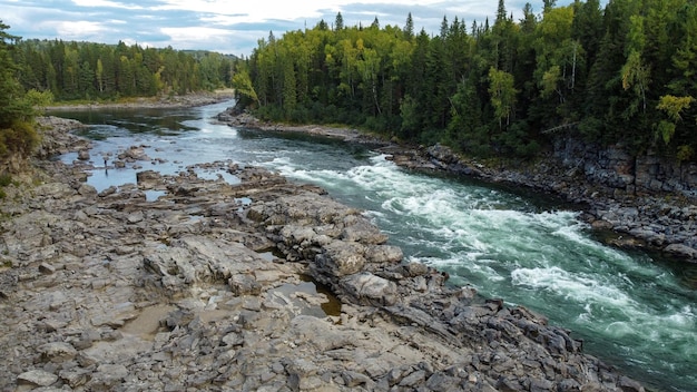 Vue de drone de paysage de nature sauvage avec rivière et forêt. Débit de la rivière sibérienne de montagne, eau sur pierre