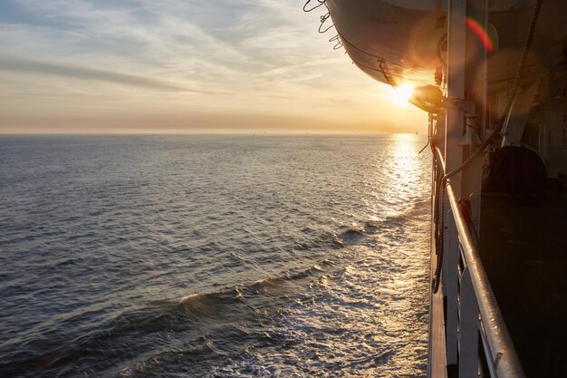 Photo vue du coucher de soleil sur les vagues sur un ferry transportant des véhicules et des passagers du port de rotterdam