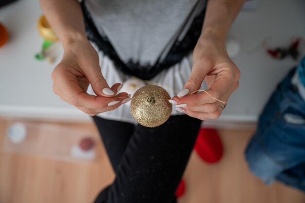 Photo vue du haut d'une femme attachant une ficelle dorée à un bijou de fête de noël brillant