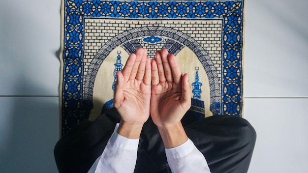Vue du haut de l'homme musulman avec la main priant sur le tapis de prière