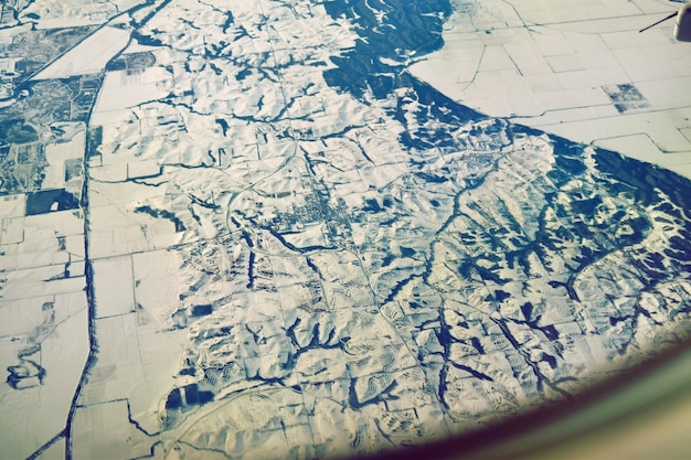 Vue du paysage couvert de neige à travers la fenêtre d'un avion
