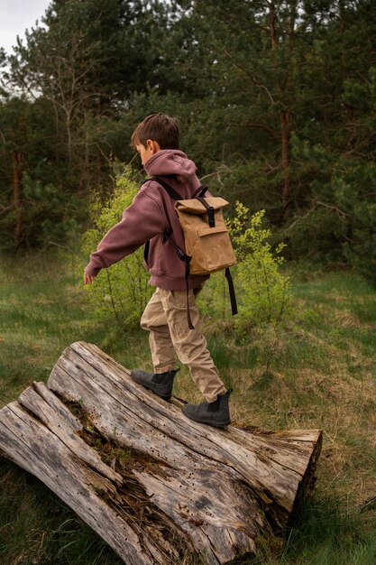 Photo vue du petit garçon avec sac à dos explorant la nature