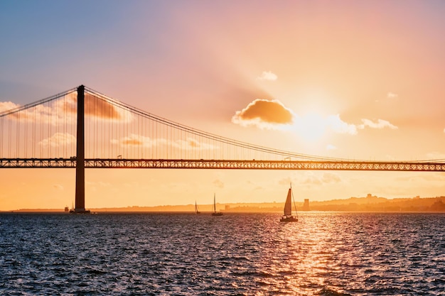 Photo vue du pont 25 de abril sur le tage au coucher du soleil lisbonne portugal