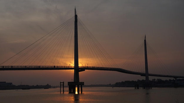 Vue du pont suspendu sur la rivière au coucher du soleil