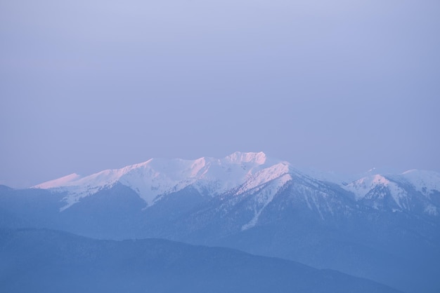 Vue du sommet de la montagne dans la neige. Paysage d'hiver avec la lumière du soleil de l'aube du matin. Couleurs pastel dans la nature