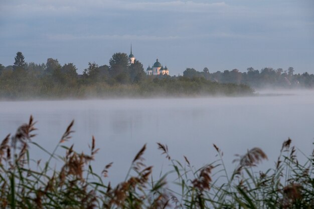 Vue de l'église de l'autre côté de la rivière dans un matin brumeux à l'aube.