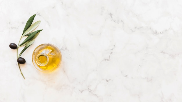 Vue élevée de la bouteille d&#39;huile d&#39;olive avec une brindille sur fond de marbre