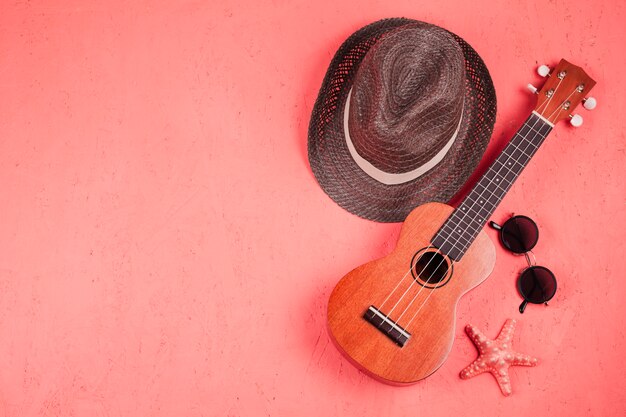 Photo une vue élevée de l'ukulélé; des lunettes de soleil; étoile de mer et chapeau sur fond de corail