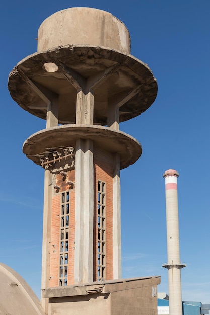 Vue d'un entrepôt abandonné élevé au-dessus d'une tourelle et en arrière-plan une grande cheminée industrielle Sagunto Valence Espagne