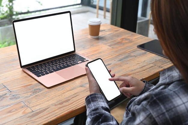 Vue sur l'épaule d'une femme d'affaires assise au bureau et utilisant un téléphone portable