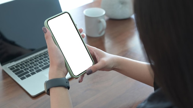 Vue sur l'épaule d'une femme utilisant un téléphone portable et un ordinateur portable au café