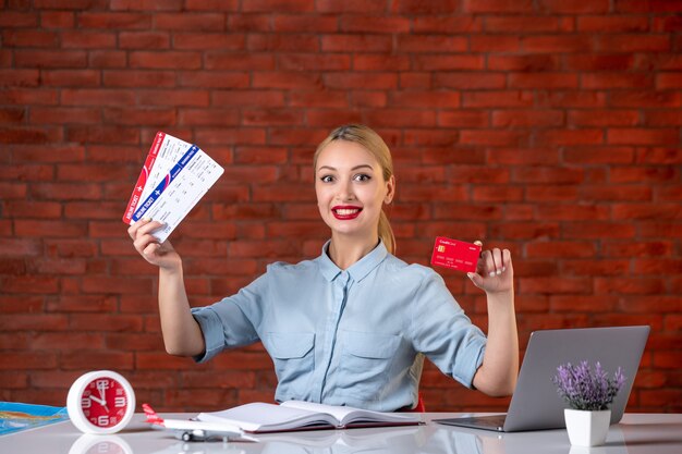 vue de face de l'agent de voyage détenant des billets et assistant de carte de crédit rouge agence d'occupation mondiale argent travail de directeur de travail professionnel