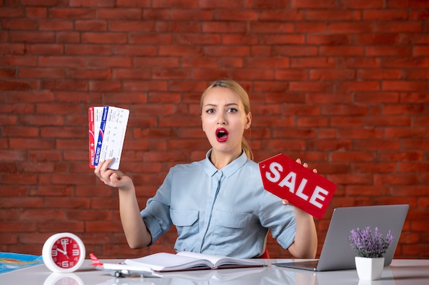 vue de face de l'agent de voyage détenant des billets et de la plaque signalétique de vente assistant directeur mondial agence d'occupation travail professionnel