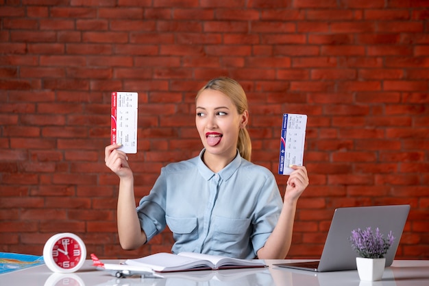 vue de face de l'agent de voyages assis derrière son lieu de travail tenant des billets gestionnaire global agence carte occupation assistant tourisme vol à l'intérieur