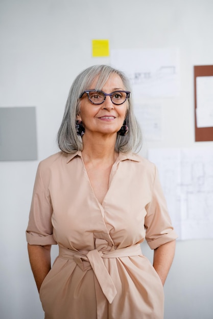 Vue de face d'une belle femme architecte senior debout à l'intérieur de la maison, les mains dans les poches.