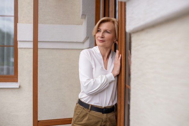 Vue de face d'une belle femme caucasienne mûre réfléchie calme appuyée contre une porte en bois