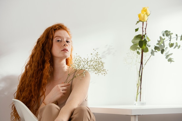 Vue de face de la belle femme avec des fleurs de printemps dans un vase