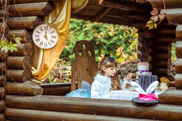 Vue de face d'une belle petite fille tenant un morceau de gâteau sur une cuillère à la table