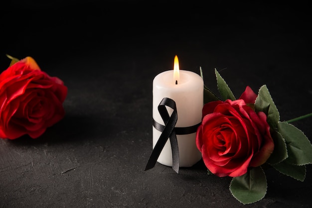 Vue de face d'une bougie blanche avec une rose rouge sur fond noir